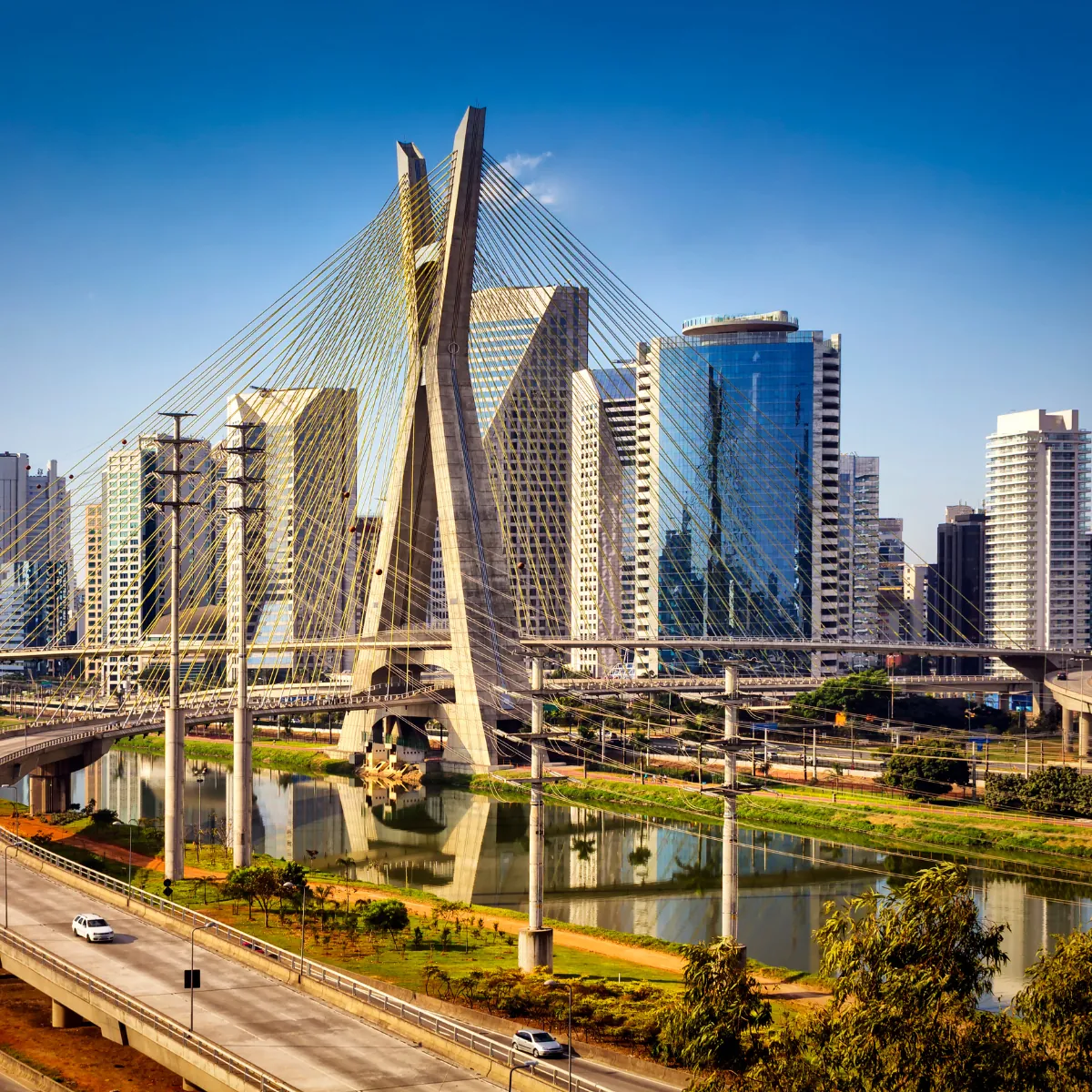 Ponte estaiada sobre rio com prédios comerciais ao fundo